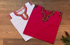 Blusa blanca para niña con bolitas y bordados de color en cuello y mangas.