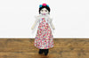 Muñeca Frida de tela con vestido floreado y rostro pintado a mano. 